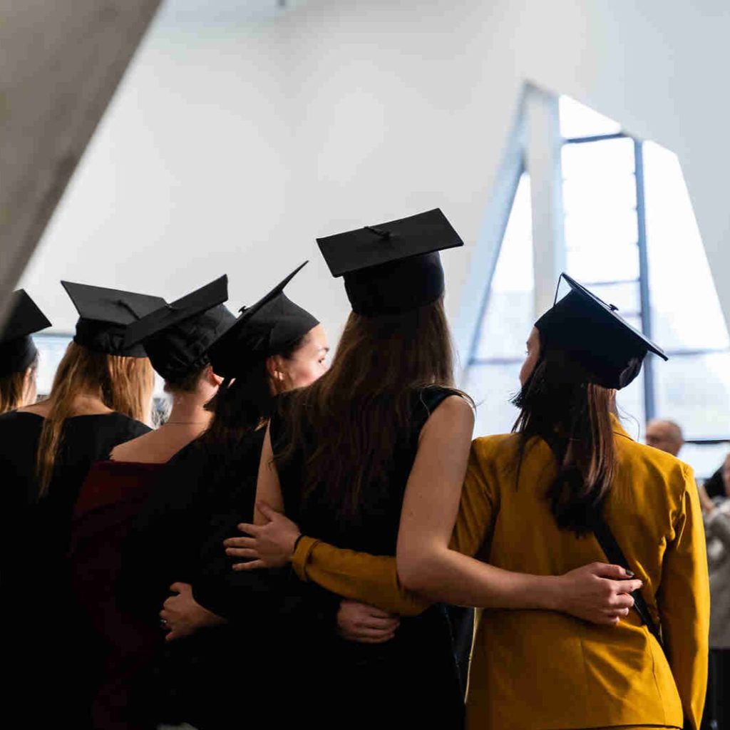 Graduation ceremony in Leuphana's central building: The image shows the backs of several people wearing graduation caps while being photographed